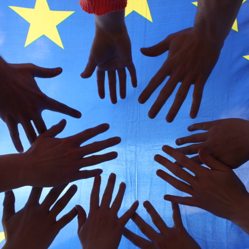 Symbolbild: Hände vor Europafahne.